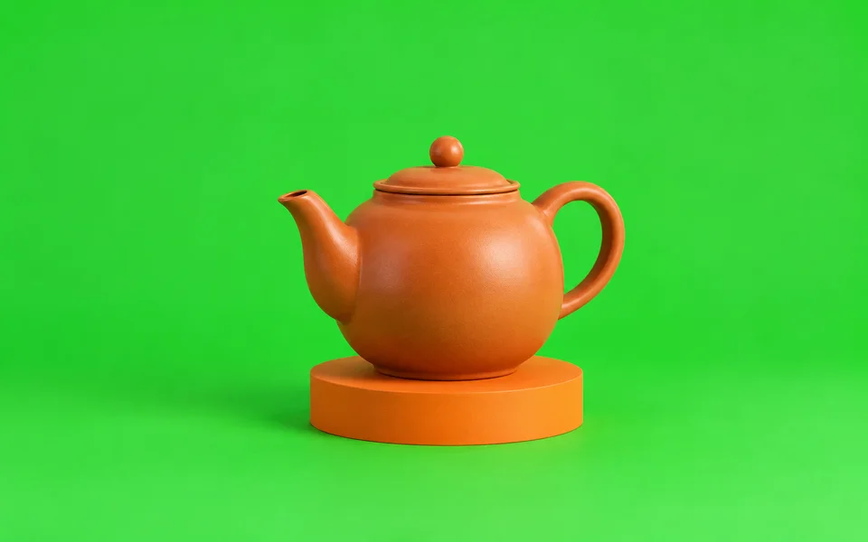Clay teapot on an orange pedestal against a green backdrop.